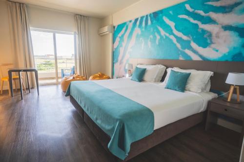 a bedroom with a large bed with a painting on the wall at Star inn Peniche in Peniche