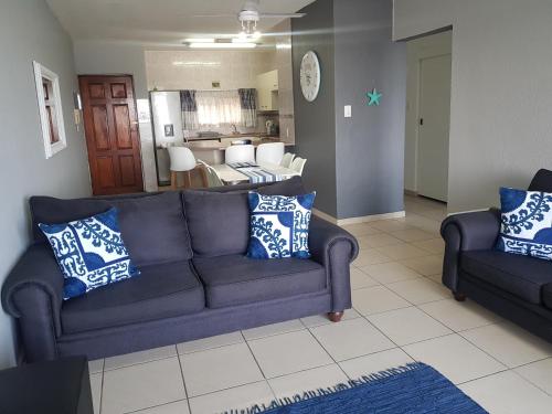 ein Wohnzimmer mit einem blauen Sofa und 2 Stühlen in der Unterkunft 17 Isikhulu in Umdloti