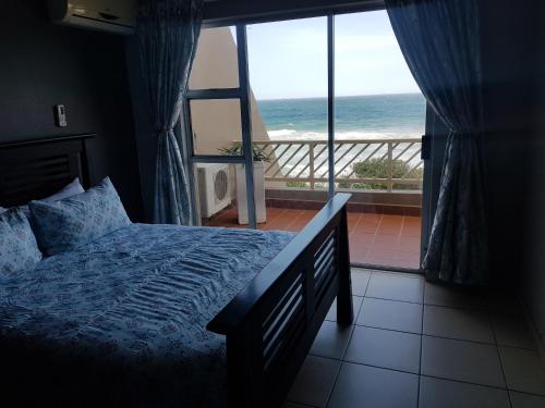 ein Schlafzimmer mit Bett und Blick auf das Meer in der Unterkunft 17 Isikhulu in Umdloti