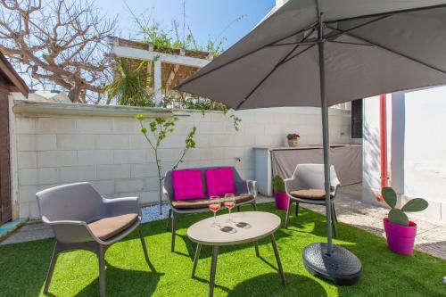 a patio with chairs and a table and an umbrella at Casa Rosa a 50mt dal mare in Torre Santa Sabina