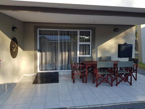a patio with a table and chairs and a television at Tlou Safari Lodge in Kasane