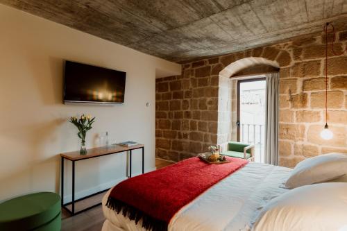 a bedroom with a bed and a tv on a brick wall at Palacio Condes de Cirac in Villalba de Rioja