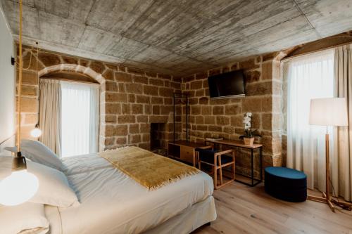 a bedroom with a bed and a brick wall at Palacio Condes de Cirac in Villalba de Rioja