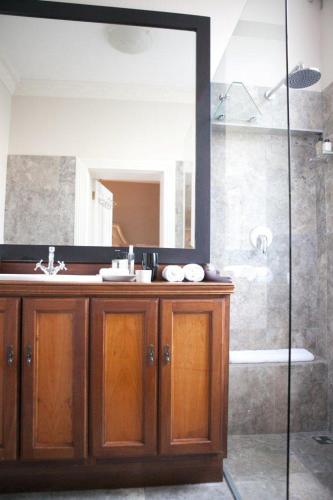 a bathroom with a sink and a shower with a mirror at Banksia Boutique Hotel & Spa in Cape Town