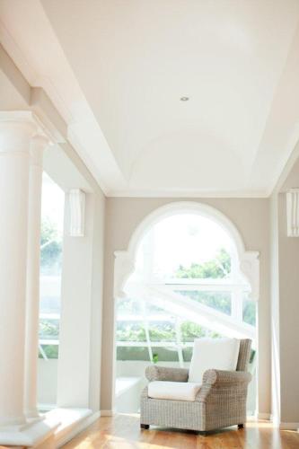 a white room with a chair in front of a window at Banksia Boutique Hotel & Spa in Cape Town