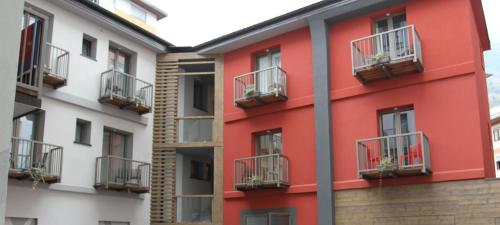 a red building with balconies on the side of it at Hotel Bed & Rooms , Corte Rossa -1 Min Walk To Bernina Express in Tirano