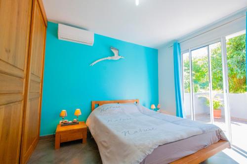 een blauwe slaapkamer met een bed en een vogel aan de muur bij "Entre Mer et Montagne" in Le Tampon