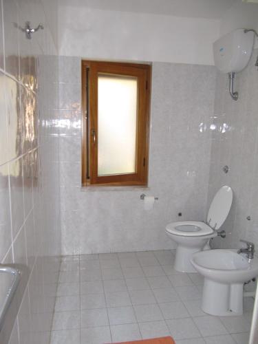 a bathroom with a toilet and a sink and a window at Agriturismo Torre Del Golfo in Cropani