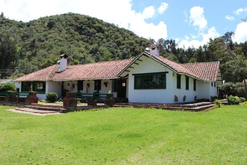 a white house with a mountain in the background at Hostal San Nicolás in Ubaté