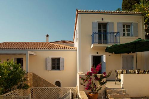 a white house with a patio and an umbrella at VILLA AELIA in Spetses - charm & convenience, 2min beach in Spetses