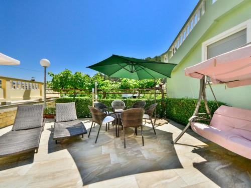 a patio with a table and chairs and an umbrella at Apartment Olga-5 by Interhome in Rab