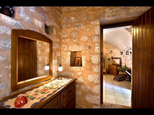 a bathroom with a mirror and a stone wall at Arapakis Historic Castle in Pirgos Dhirou