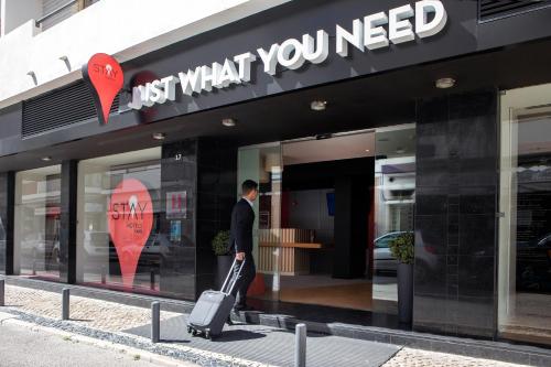 a man walking in front of a store with a suitcase at Stay Hotel Faro Centro in Faro