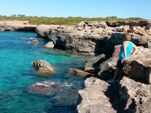 a woman standing on some rocks in the water at Ca Na Clar in Sa Ràpita