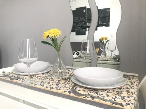 un tavolo con piatti e bicchieri e un vaso con fiori di Apartamento Conocedores a Jerez de la Frontera