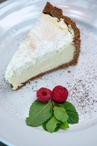 a piece of cake on a white plate with two raspberries at Nkomazi Kruger Lodge & Spa in Malelane