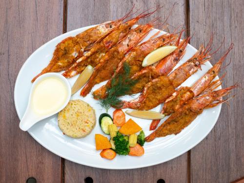 a plate of food with shrimp and vegetables on a table at Nkomazi Kruger Lodge & Spa in Malelane