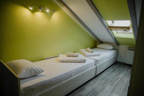 two beds in a small room with green walls at Pansion Fočin Han in Sarajevo