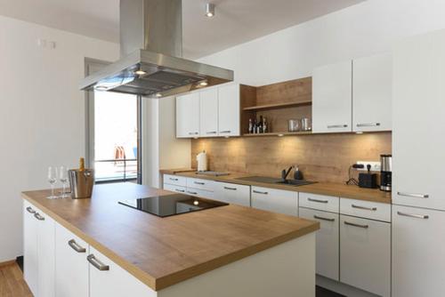 a kitchen with white cabinets and a wooden counter top at Seechalet in Altossiach
