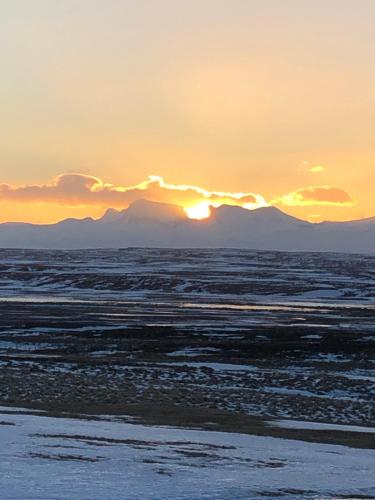 a sunset over a field with mountains in the background at Guesthouse Svartiskógur Egilsstaðir in Svartiskogur