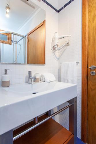 a white bathroom with a sink and a mirror at Casas Ponte D'Alge in Foz de Alge