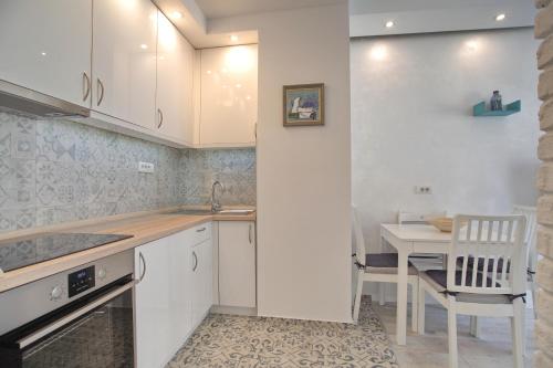 a kitchen with white cabinets and a table with a chair at Bianca in Belgrade