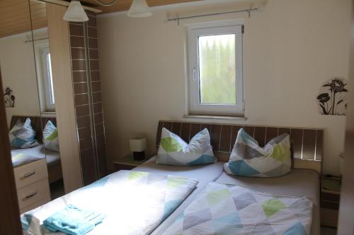 ein Schlafzimmer mit einem Bett mit Kissen und einem Fenster in der Unterkunft Bungalow Groß Dratow in Groß Dratow