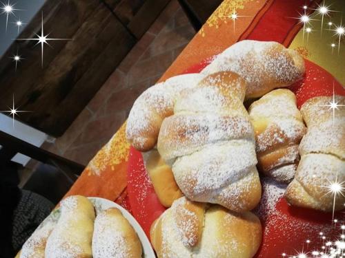 a bunch of donuts on a red tray with powdered sugar at La Casa del susino in Castiglione dʼOrcia