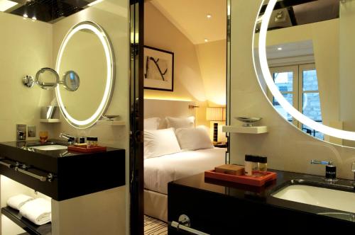 W łazience znajduje się łóżko, umywalka i lustro. w obiekcie Hotel Montaigne w Paryżu