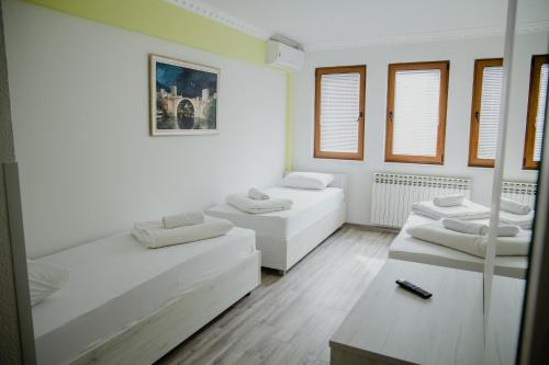 three beds in a room with white walls and windows at Pansion Fočin Han in Sarajevo