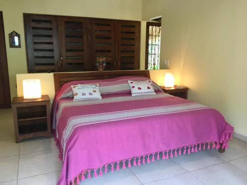 a bedroom with a large pink bed with two lamps at Un Escondite Mágico in Barra de Potosi