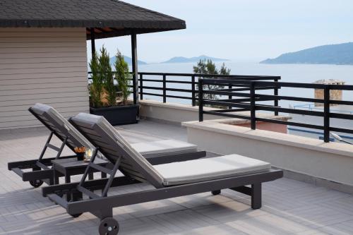 a pair of lounge chairs on a deck with the water at True Blue Boutique Hotel Kalkan in Kalkan