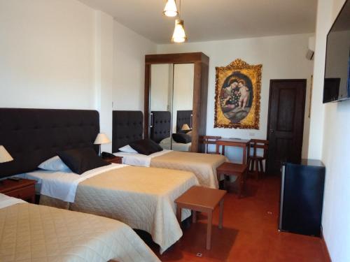 a hotel room with three beds and a television at Casa Hacienda Nasca Oasis in Nazca