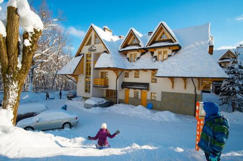 a child in the snow in front of a house at Aparthotel Bellamonte in Zakopane