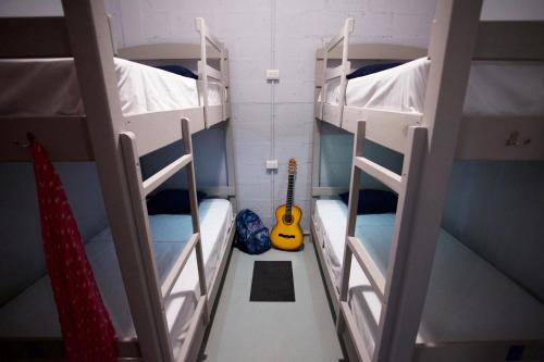a room with three bunk beds and a guitar at Hostel Auikyani in Cozumel