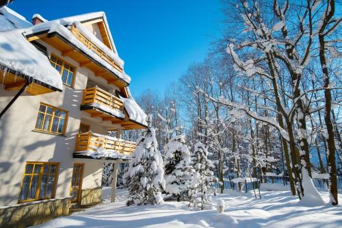 a building covered in snow with trees in the background at Aparthotel Bellamonte in Zakopane