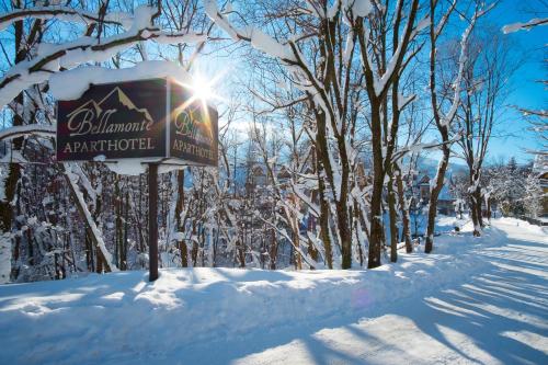 a sign in the snow next to some trees at Aparthotel Bellamonte in Zakopane