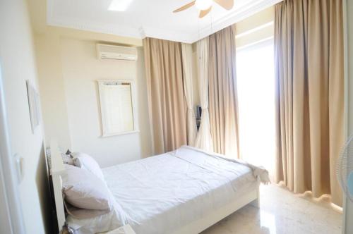 un letto bianco in una stanza con una finestra di Gold City Private Pool Villa 3+1 with Free AquaPark a Alanya