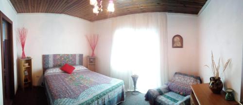 a bedroom with a bed and a chair and a window at Pensiunea La Poarta Bucovinei in Suceava