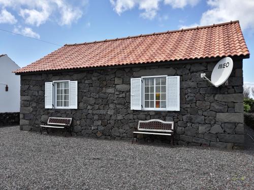 a stone building with two benches in front of it at Casa Caminho da Barca in Madalena