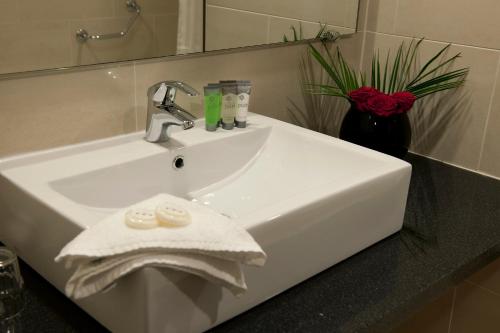 a white sink sitting under a mirror in a bathroom at Clayton Hotel Ballsbridge in Dublin