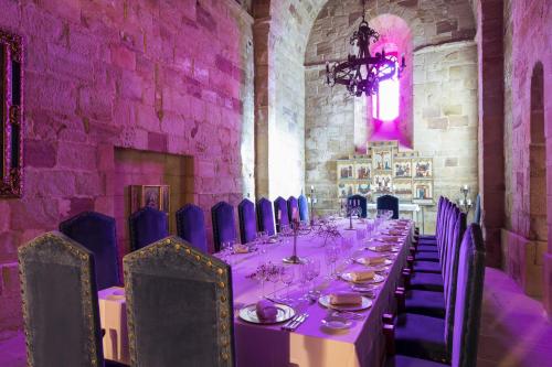 a long table in a room with blue chairs at Parador de Siguenza in Sigüenza