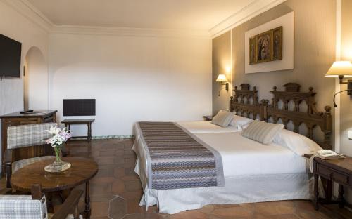 Habitación de hotel con 2 camas y mesa en Parador de Siguenza, en Sigüenza