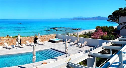 a pool with chairs and the ocean in the background at Résidence Dary in LʼÎle-Rousse