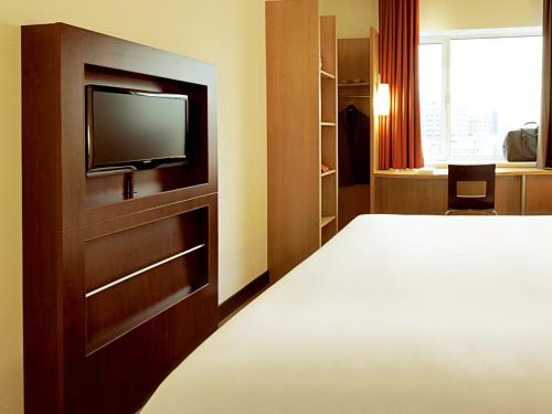 a hotel room with a bed and a flat screen tv at Hotel ibis Lisboa Jose Malhoa in Lisbon