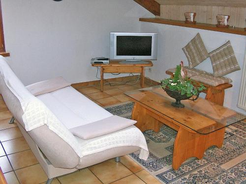een woonkamer met een stoel en een tafel met een televisie bij Apartment Les Galets by Interhome in Ocourt