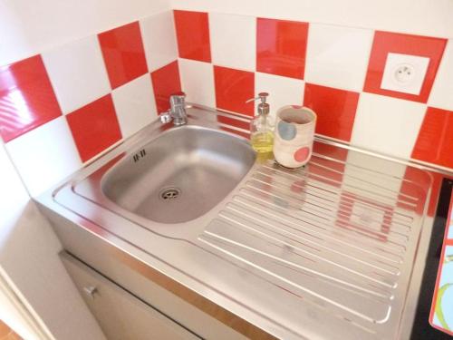 a sink in a kitchen with a red and white tiled wall at le 1835, studio rouge-Corail in Moustiers-Sainte-Marie