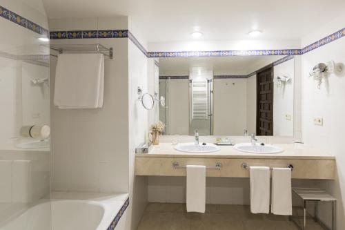 a bathroom with two sinks and a tub and a mirror at Parador de Siguenza in Sigüenza