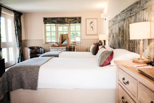 een slaapkamer met 2 bedden en een houten muur bij The White Buck in Burley