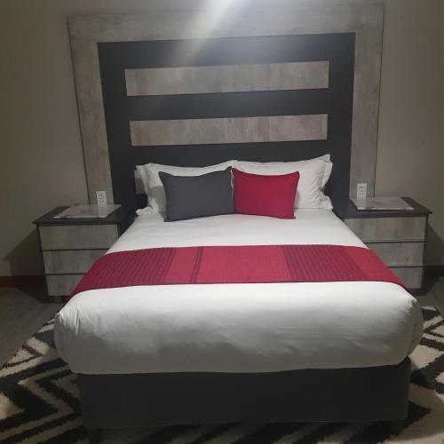 a bedroom with a large bed with a red pillow at Sagwadi Hotel in Hazyview